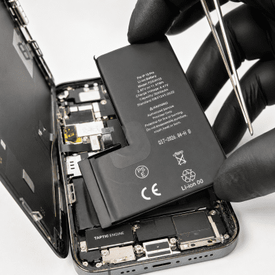 Open iPhone with battery and internal components exposed; technician in gloves handling the battery.